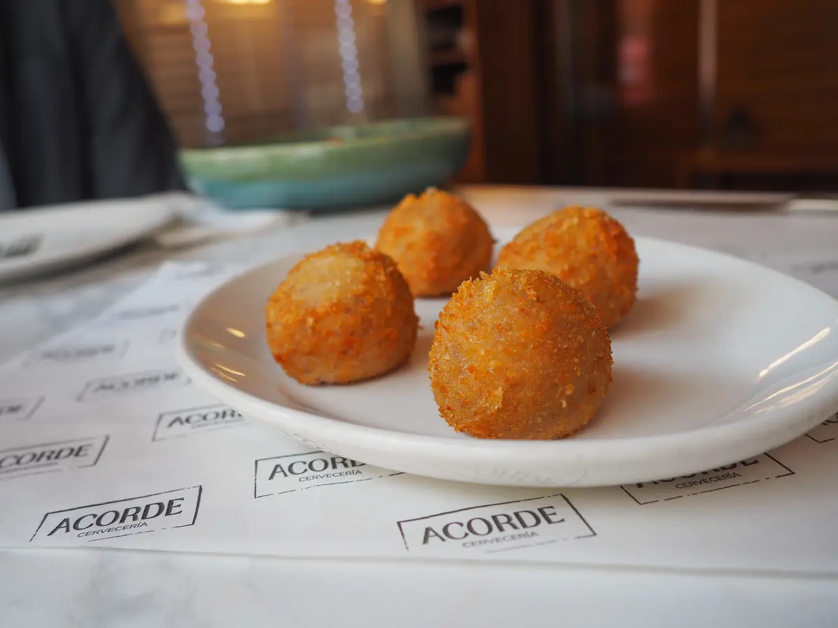 Croquetas de jamón servidas sobre papel de Cervecería Acorde